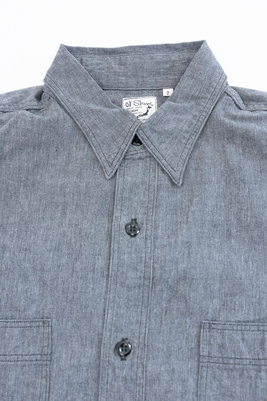 Close-up front view of a grey button-down shirt showing the collar and tag.