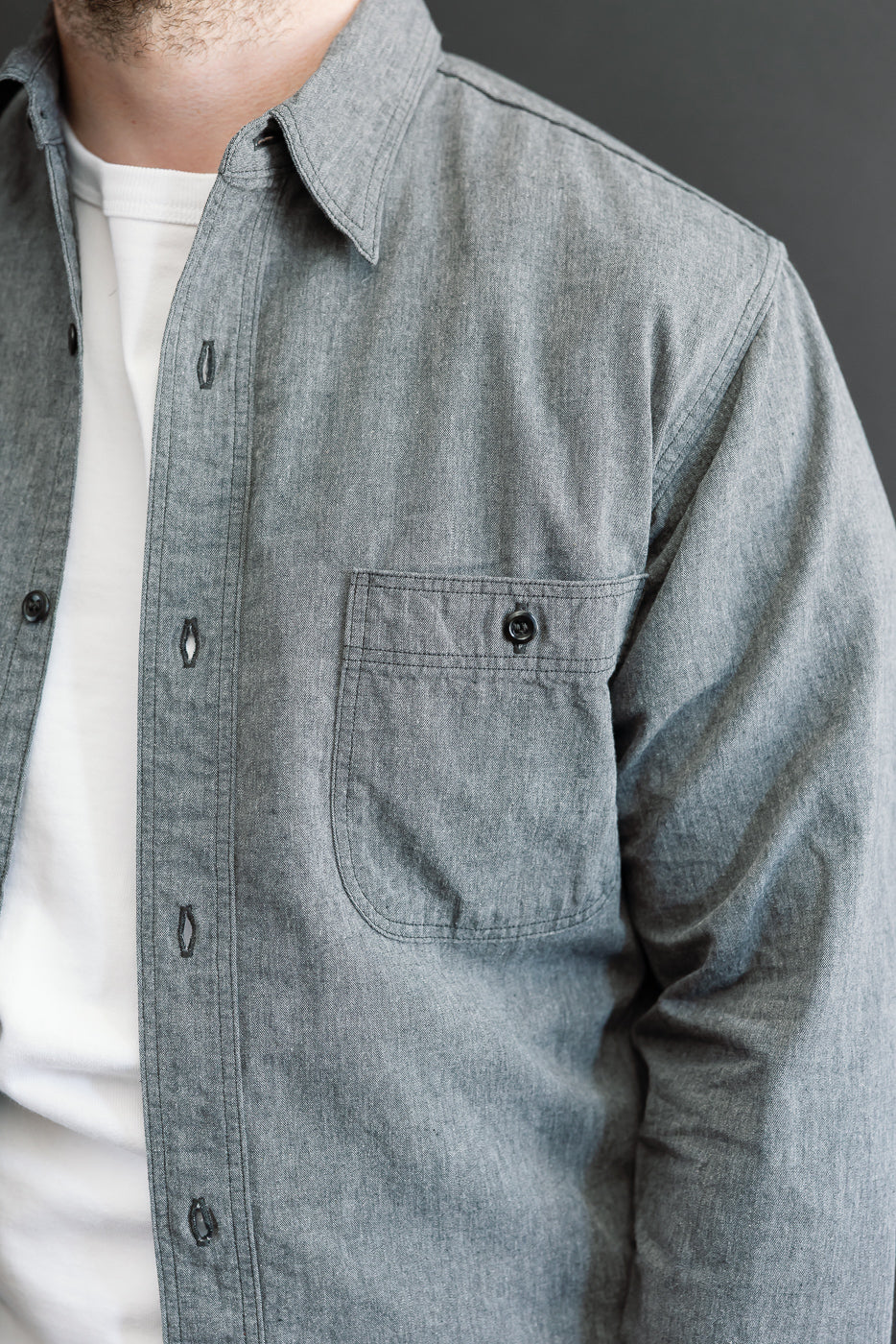 Close-up left side view of a grey button-down shirt on a male model, showing chest pocket.