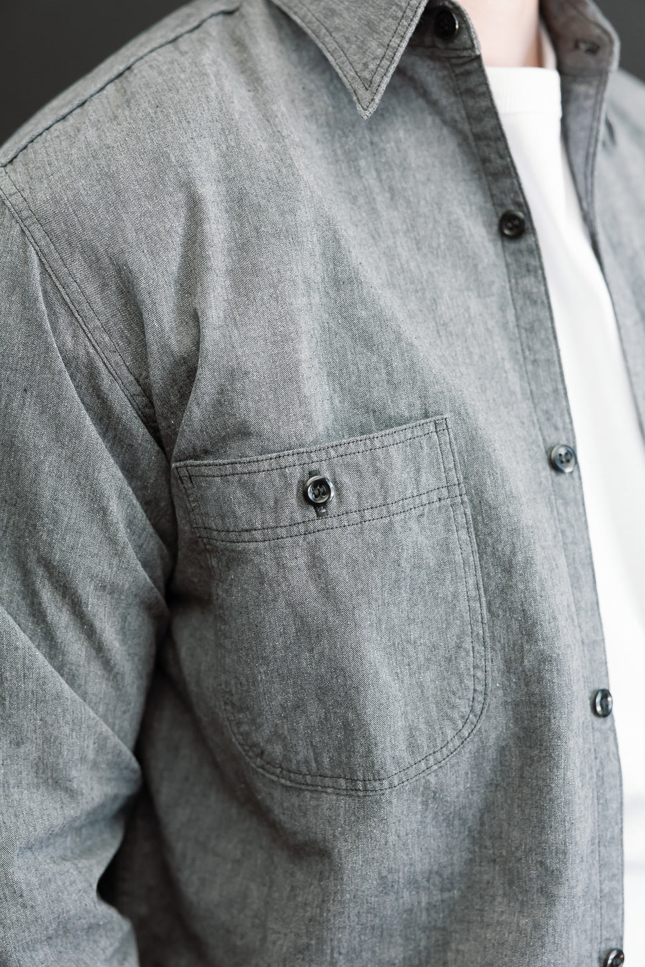 Close-up of the front chest and pocket of a grey textured button-down shirt.