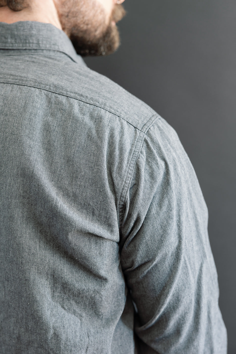 Close-up back view of a grey long-sleeve button-down shirt showing shoulder and sleeve texture.