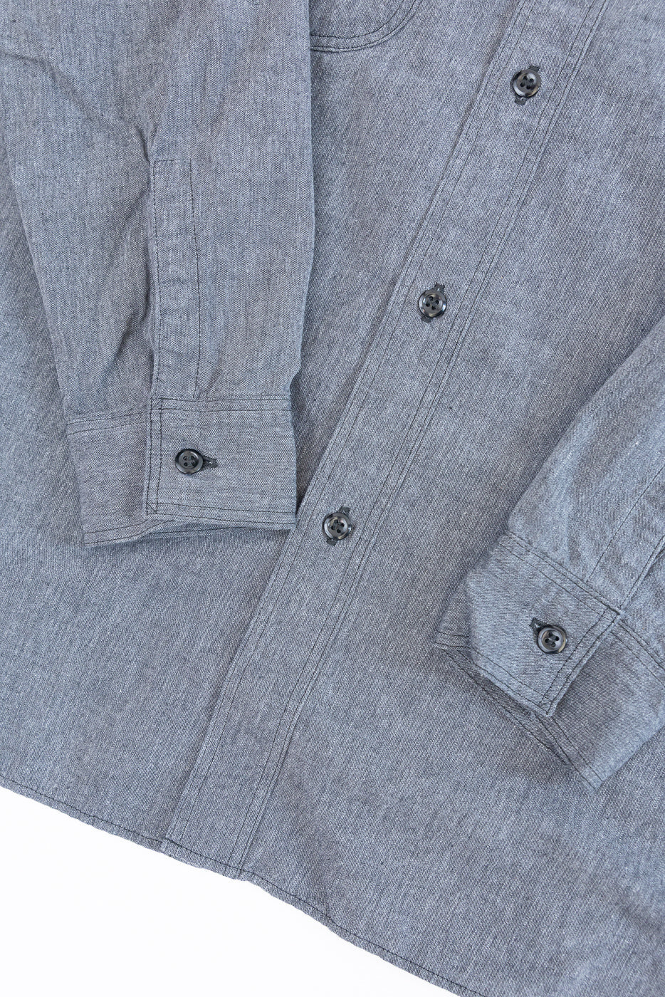 Flat lay close-up of the front of a grey button-down shirt showing fabric texture and buttons.