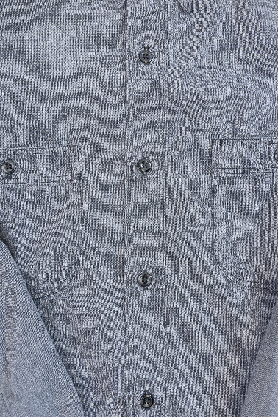 Close-up front view of a grey textured button-down shirt showing buttons and pockets.