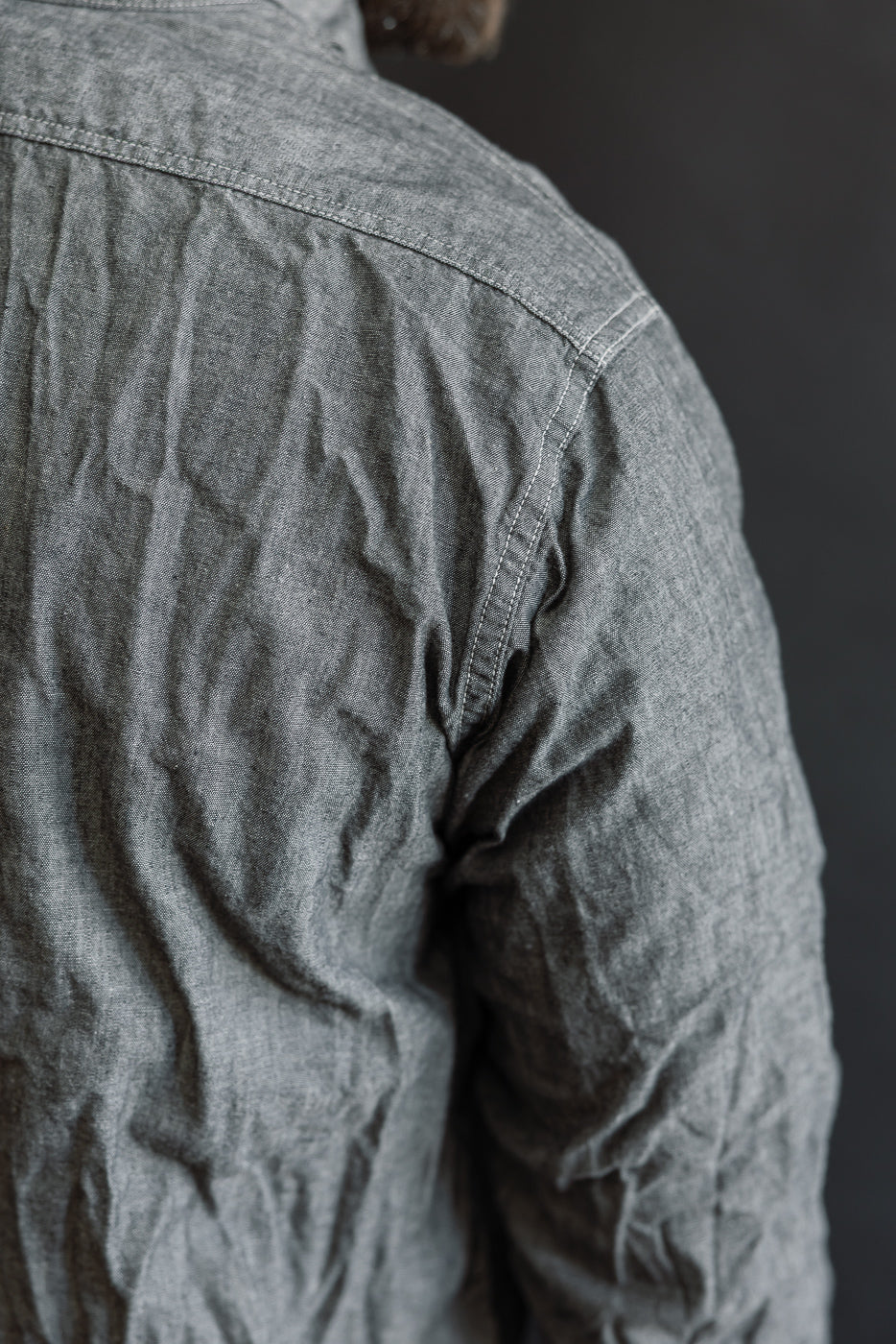 Close-up of the 01-8270-61 - Relaxed Fit Chambray Work Shirt - Black, showcasing its textured, slightly wrinkled fabric, shoulder seam, and back panel stitching, exemplifying vintage-inspired workwear craftsmanship.