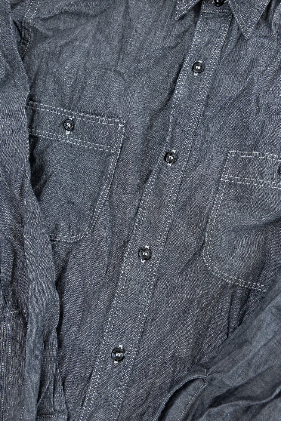 Close-up of 01-8270-61 - Relaxed Fit Chambray Work Shirt - Black, featuring a charcoal chambray fabric, black buttons, twin chest pockets with white stitching, and a slightly wrinkled texture for a vintage look.