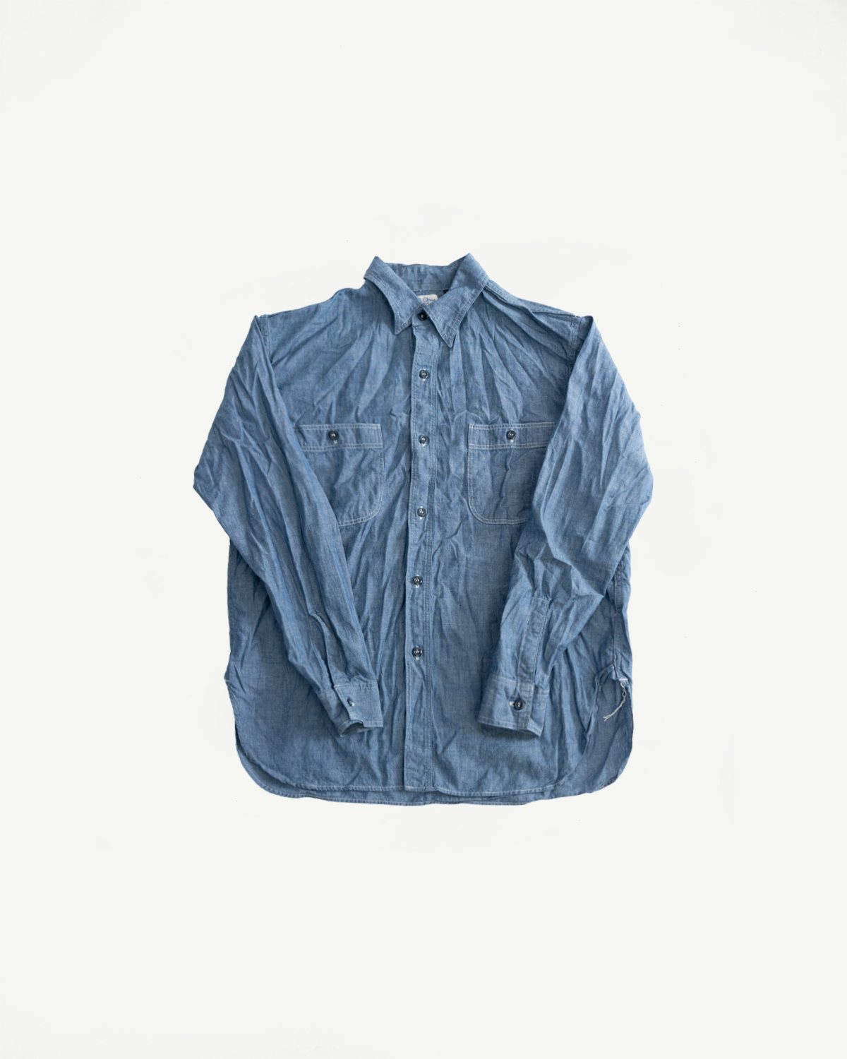 Flat lay, front view of indigo chambray work shirt with button front and flap chest pockets.