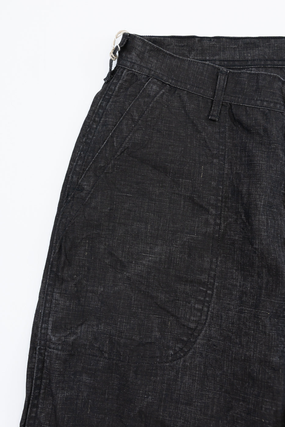 Close-up front view of dark selvedge pants, showcasing waistband, button, and fabric texture.