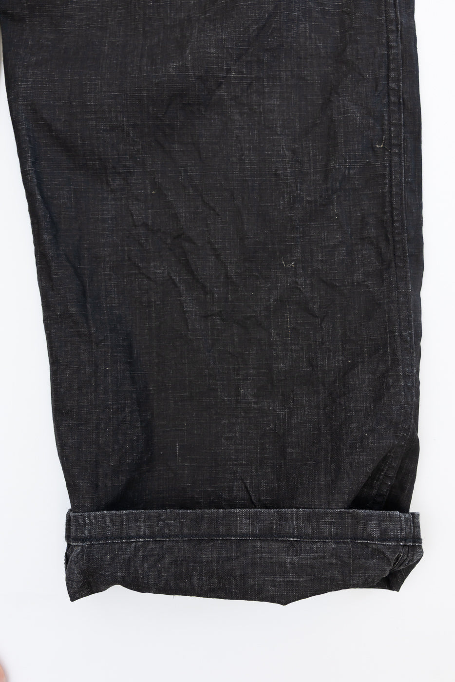 Close-up of black selvedge jeans hem, showcasing fabric texture and rolled cuff detail