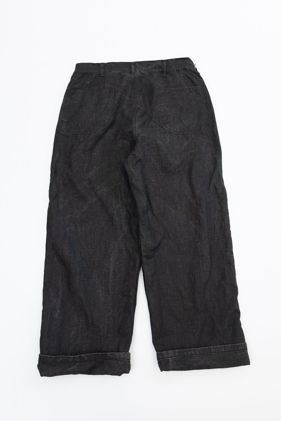 Back view flat lay of dark selvedge wide-leg pants with cuffed hems and rear pockets