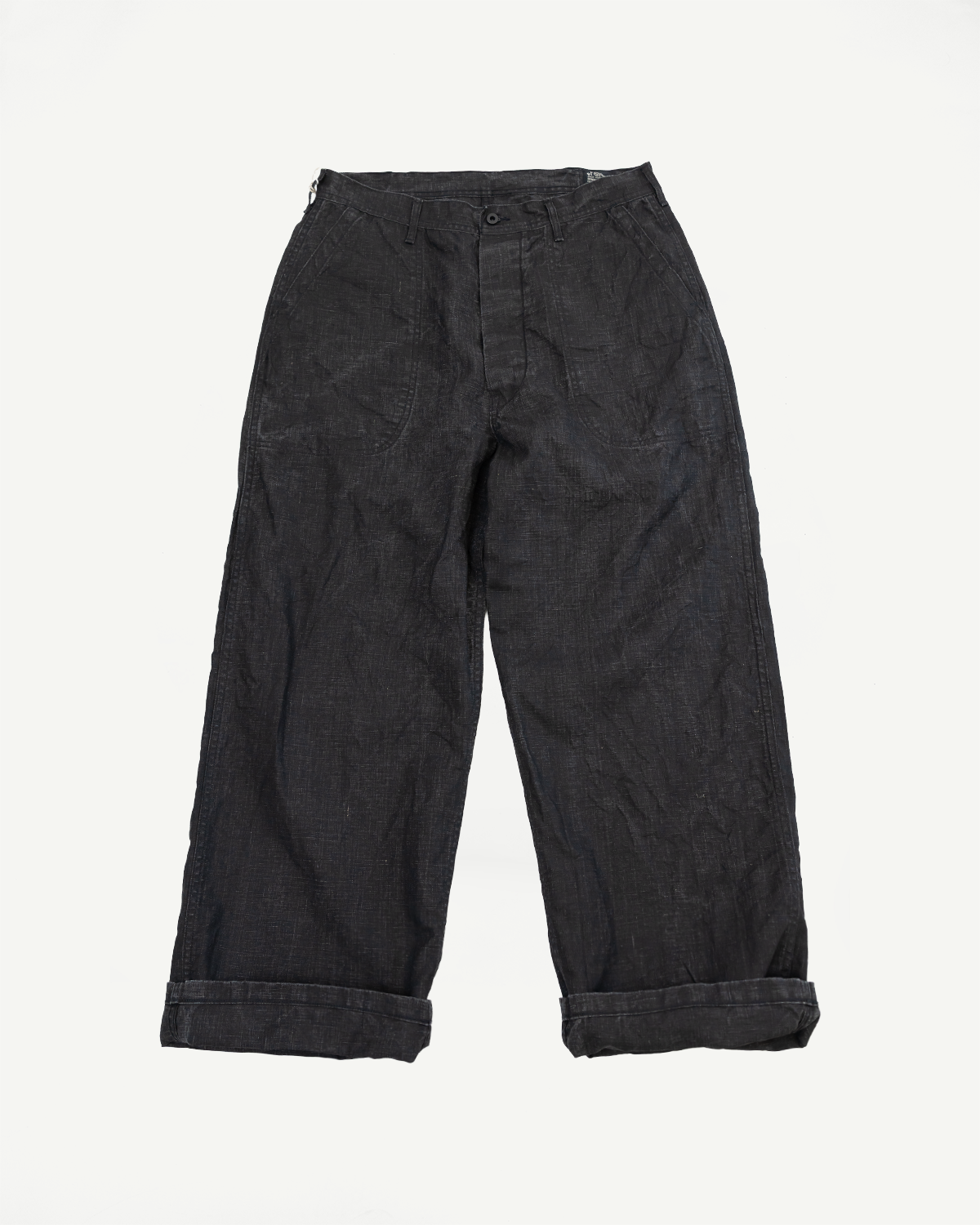 Flat lay front view of dark selvedge workwear pants with cuffed hems, button fly, and deep pockets