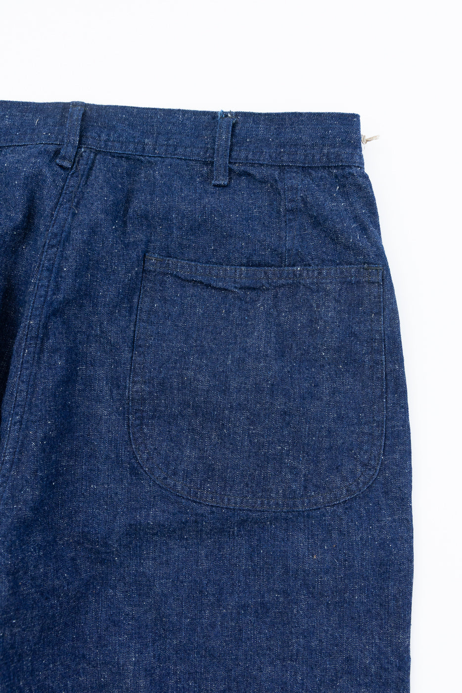 Close-up of the back of indigo selvedge denim utility pants, showing rear pocket and waistband details.