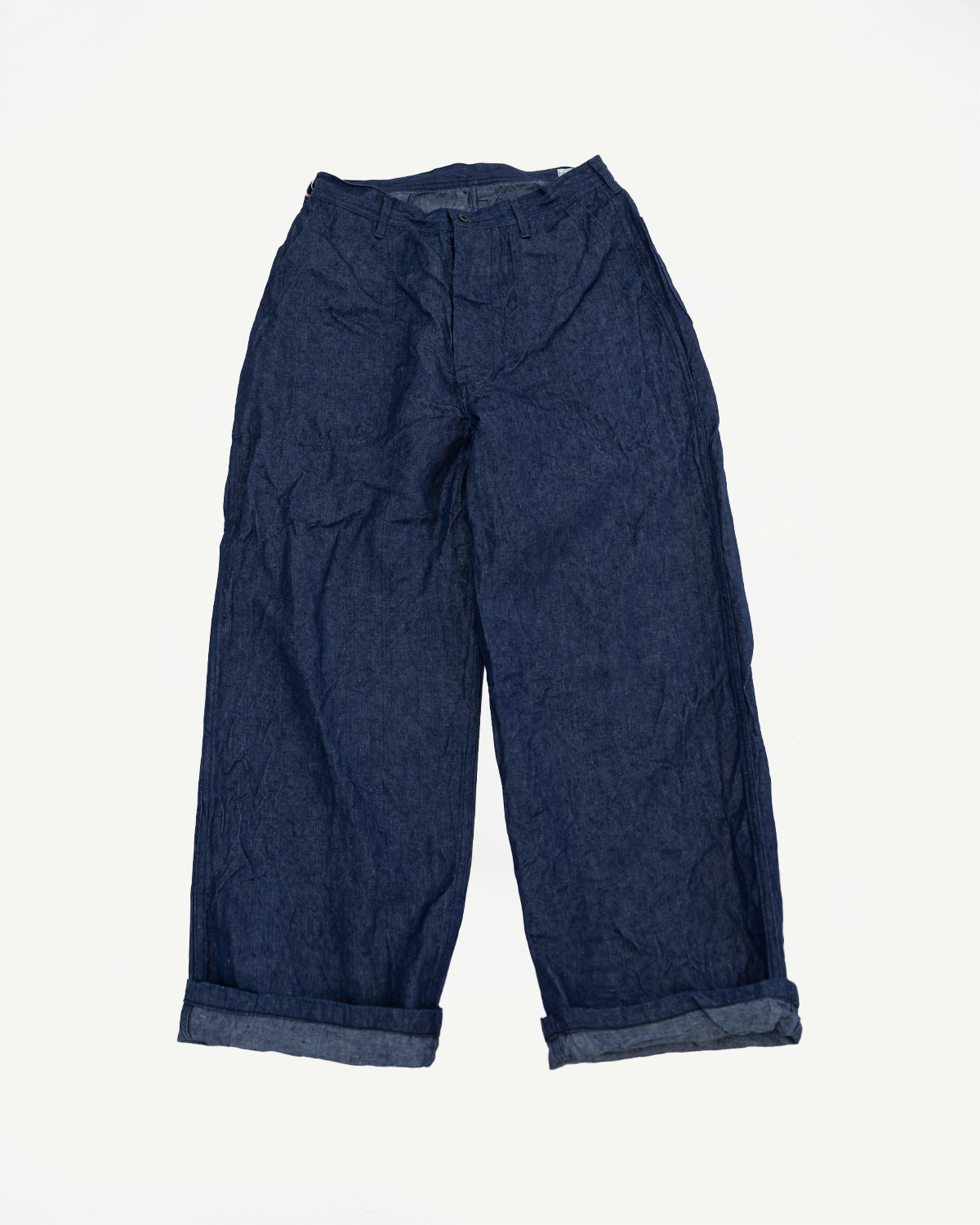 Front view flat lay of dark indigo wide-leg selvedge pants with cuffed hems, showcasing fabric texture and relaxed fit