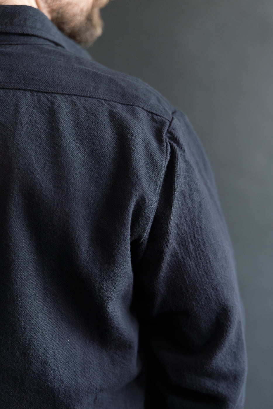 Close-up of back shoulder detail on men's navy flannel shirt, athletic male model, texture visible