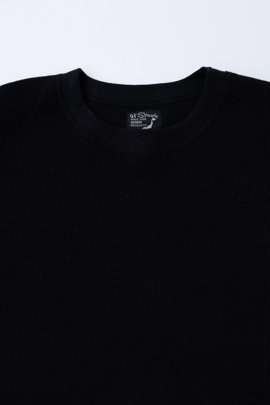 Close-up of the front ribbed crewneck collar and fabric texture of a black shirt.
