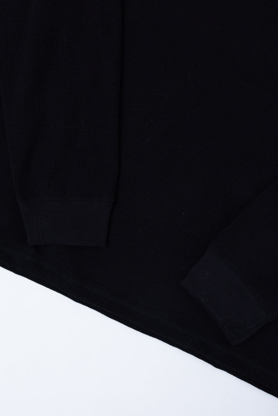 Close-up of the black ribbed fabric texture on the front of a garment sleeve and body.