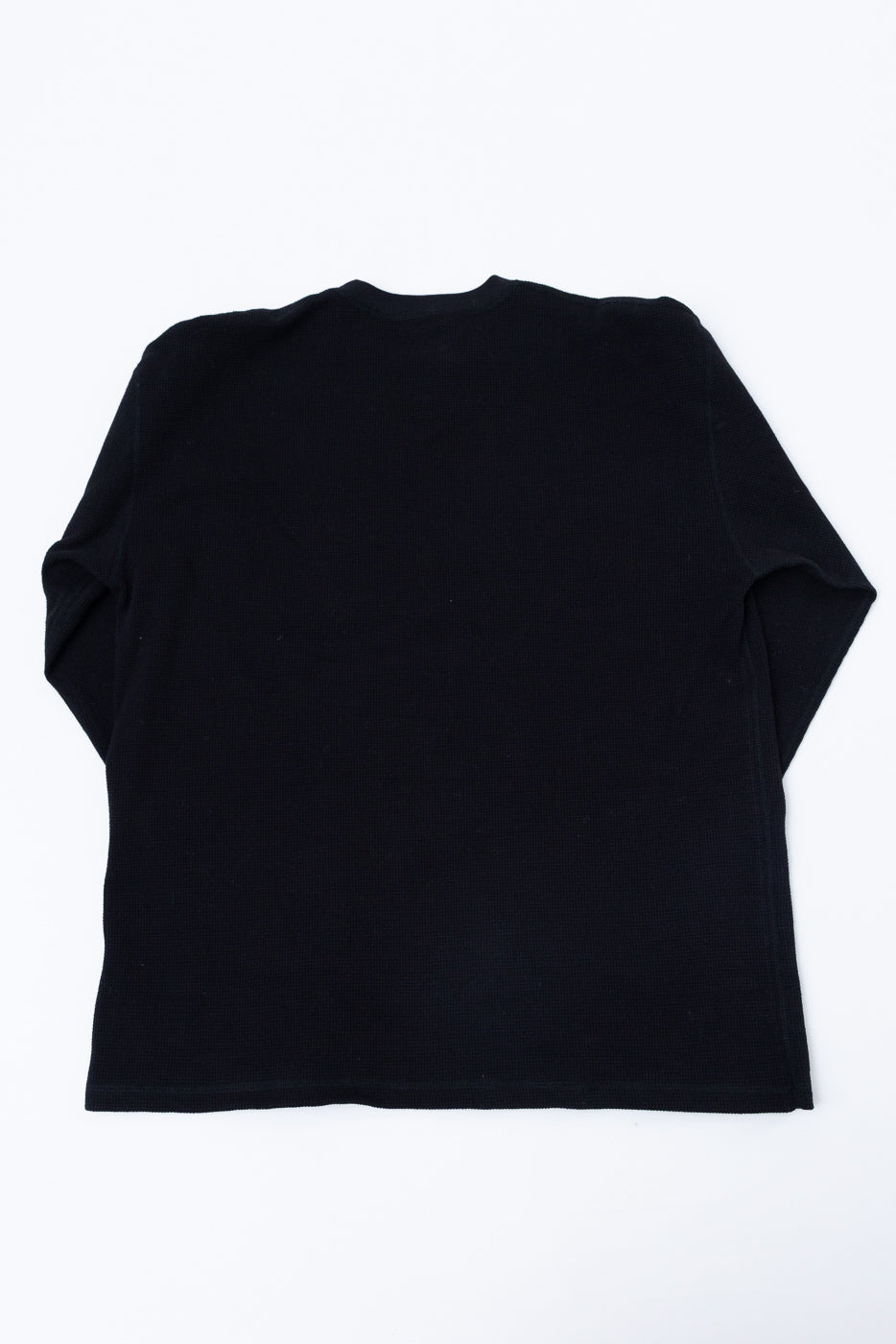 Flat lay of the back of a black long-sleeve ribbed shirt.