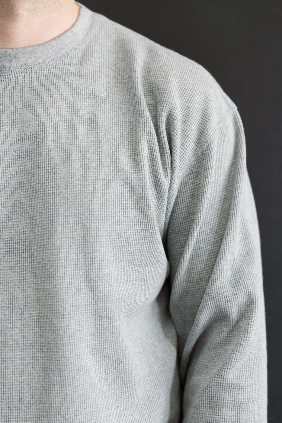 Close-up of the front and side of a grey waffle-knit shirt on a male model, 5'9