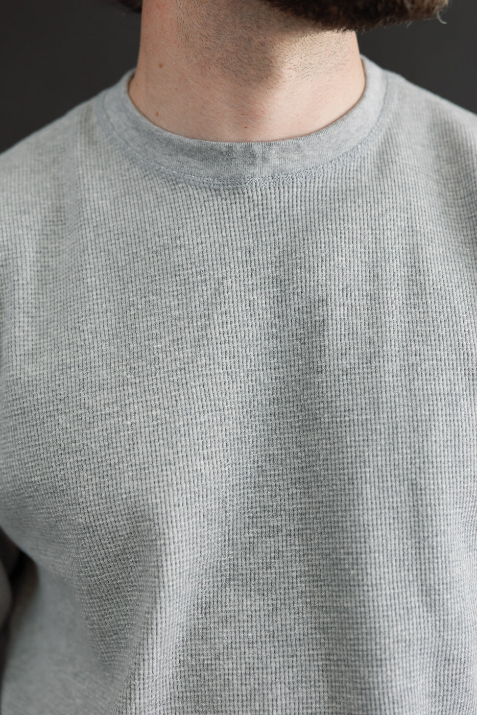 Close-up front view of a male model wearing a grey waffle knit crewneck sweatshirt.