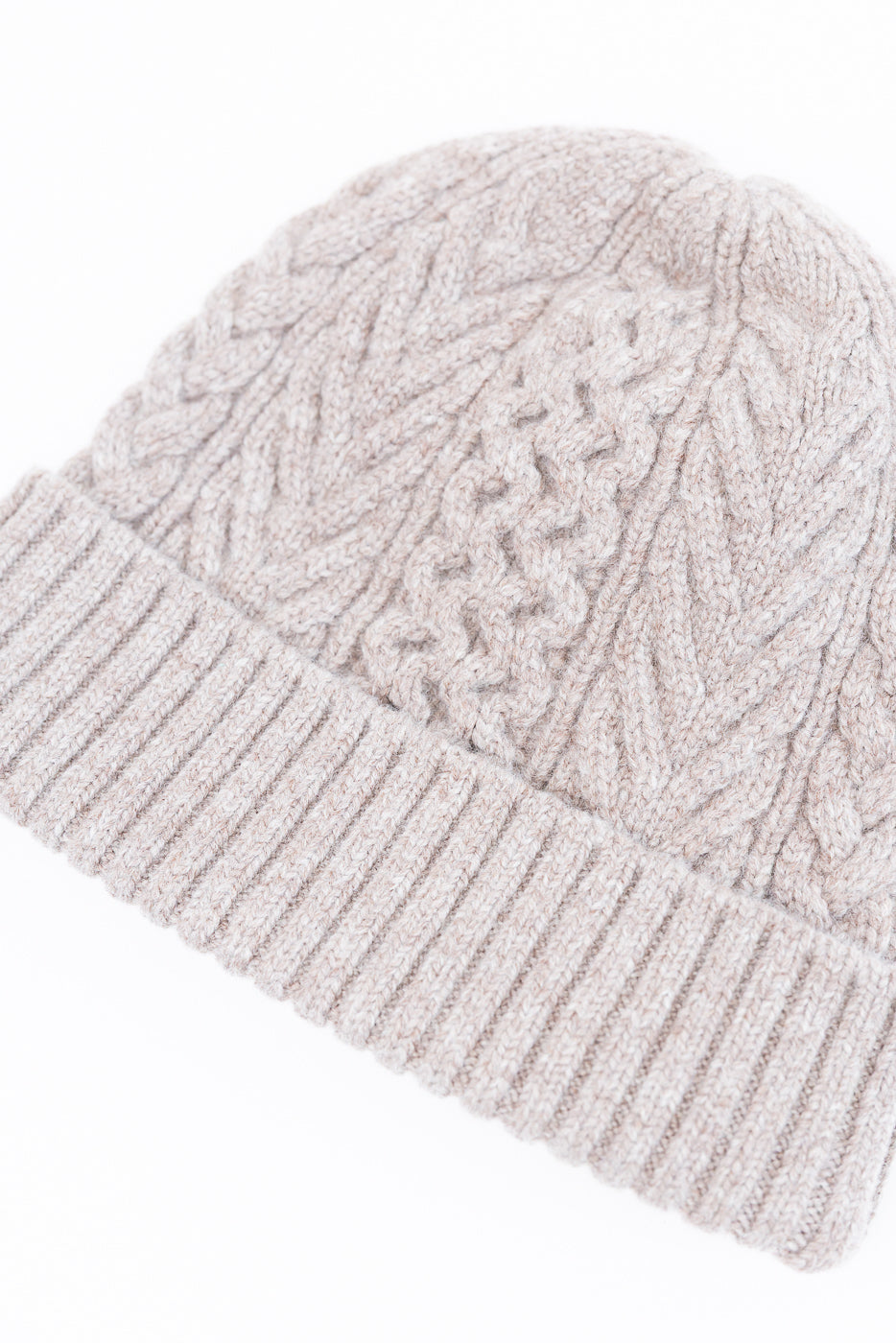 Close-up of a beige cable-knit beanie showing the detailed knit texture and ribbed brim.