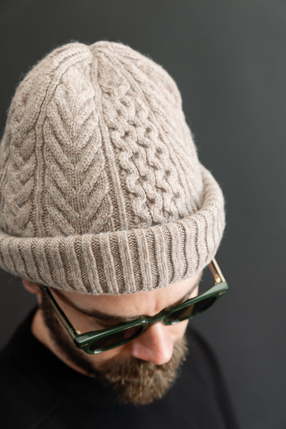 Close-up front view of a cable-knit beanie on a male model, 5'9