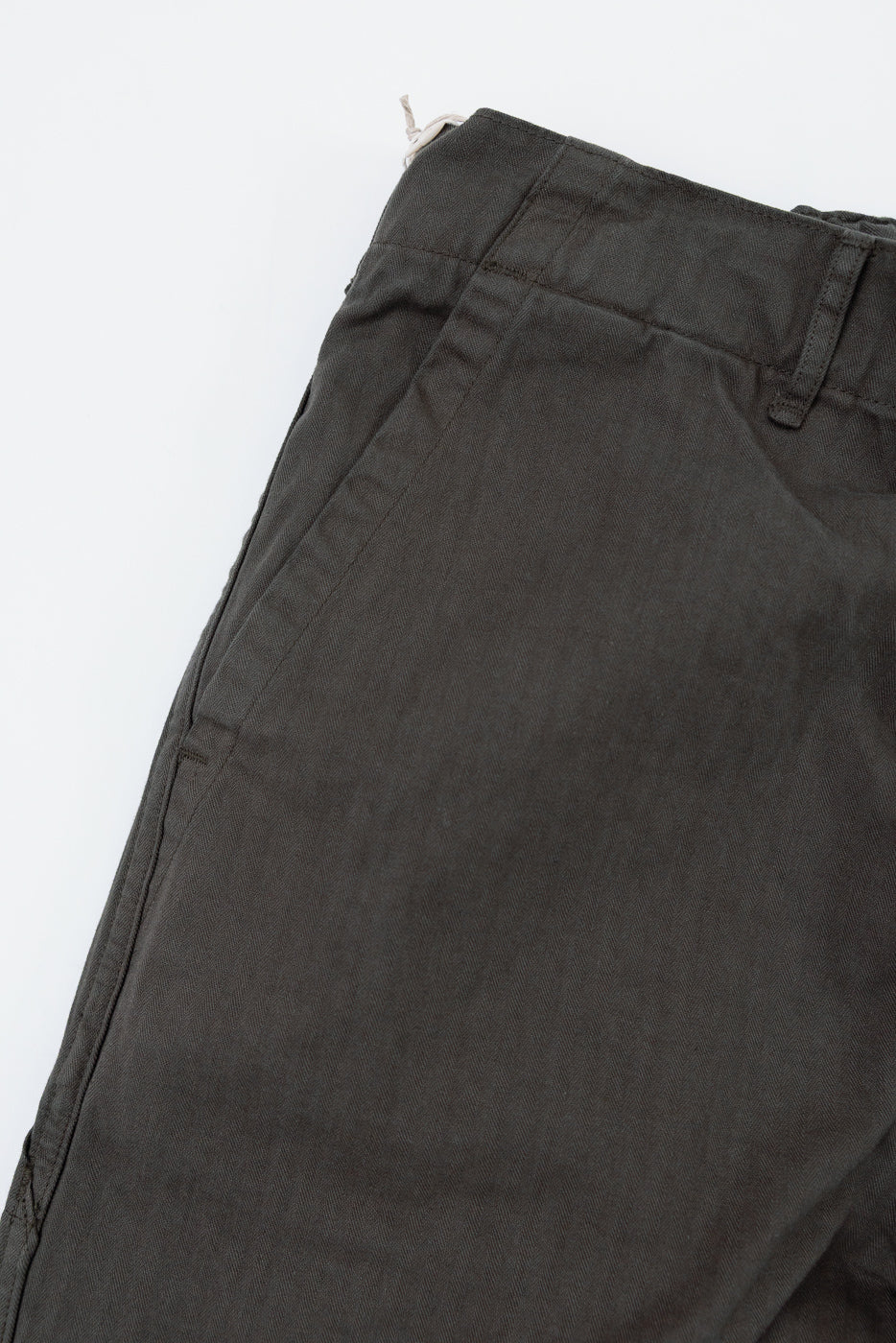 Close-up of the front waist and pocket area of dark olive green casual trousers.