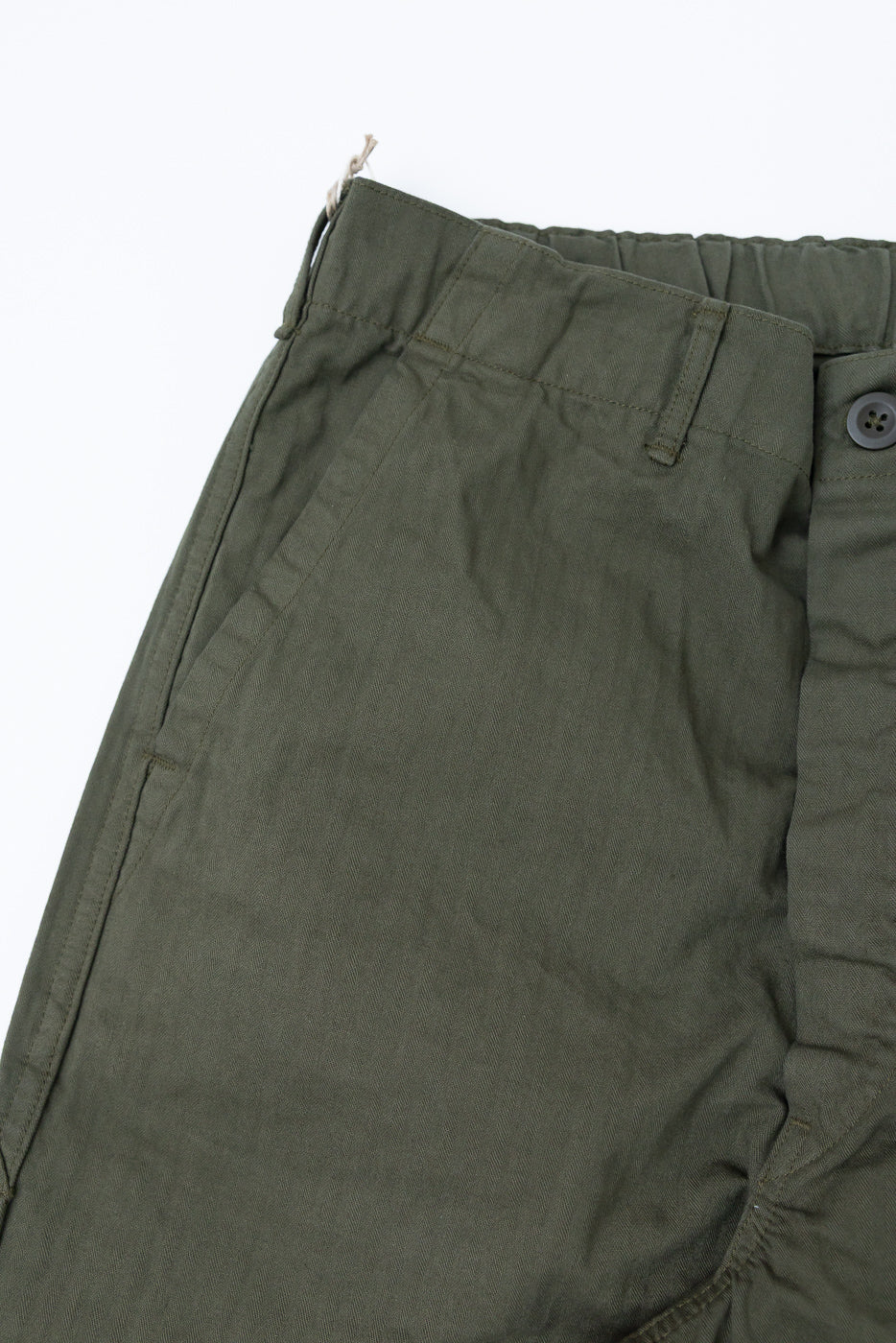 Close-up of front left waist and pocket detail on olive green wide French work pant.