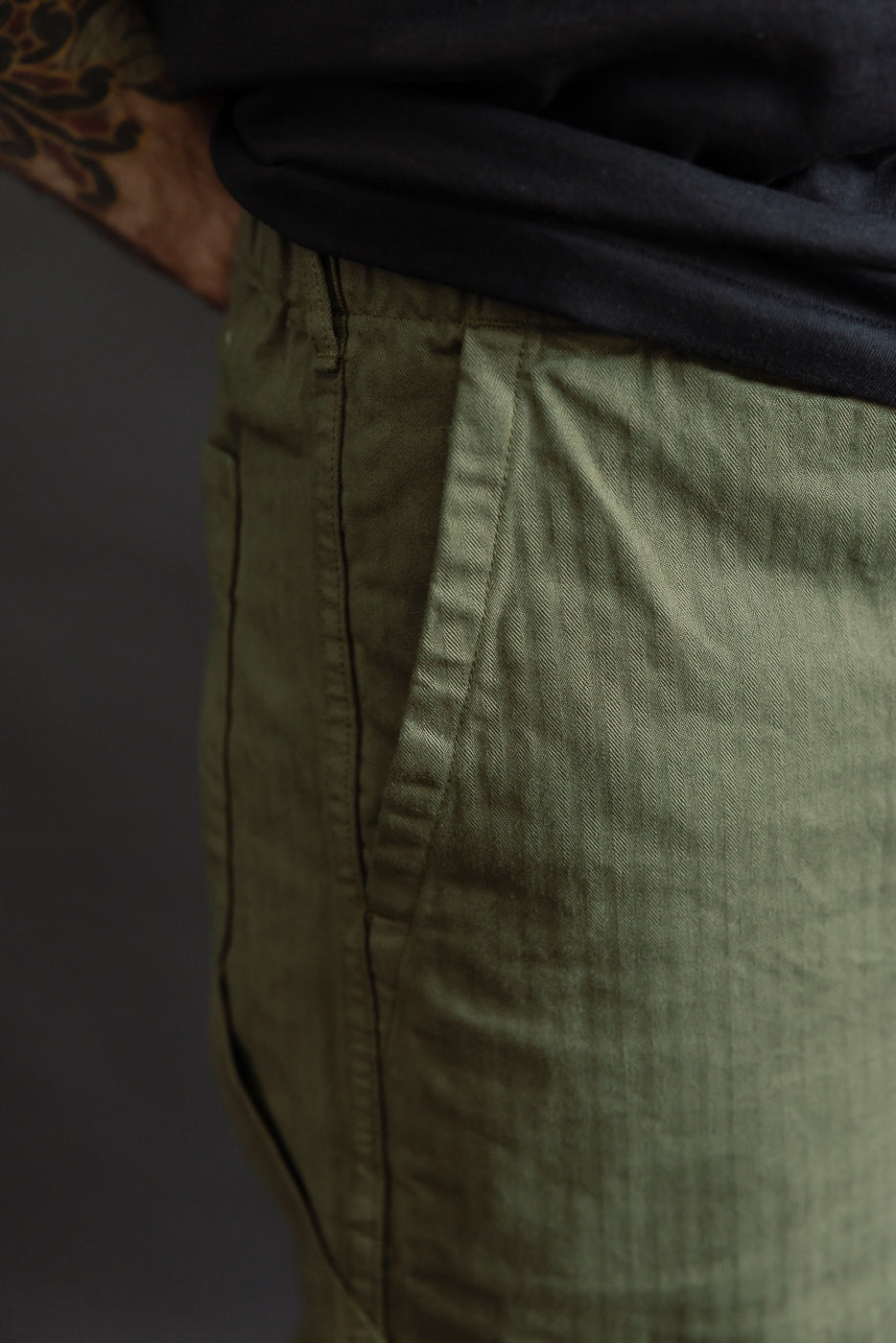 Close-up side view of army green wide French work pant pocket detail on male model, 5'9