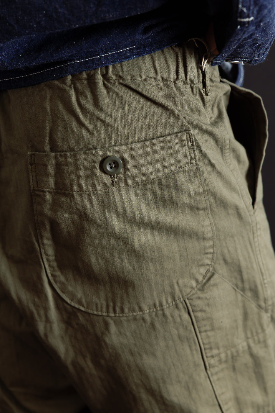 Close-up of the back right pocket of olive green trousers on a male model, 5'9