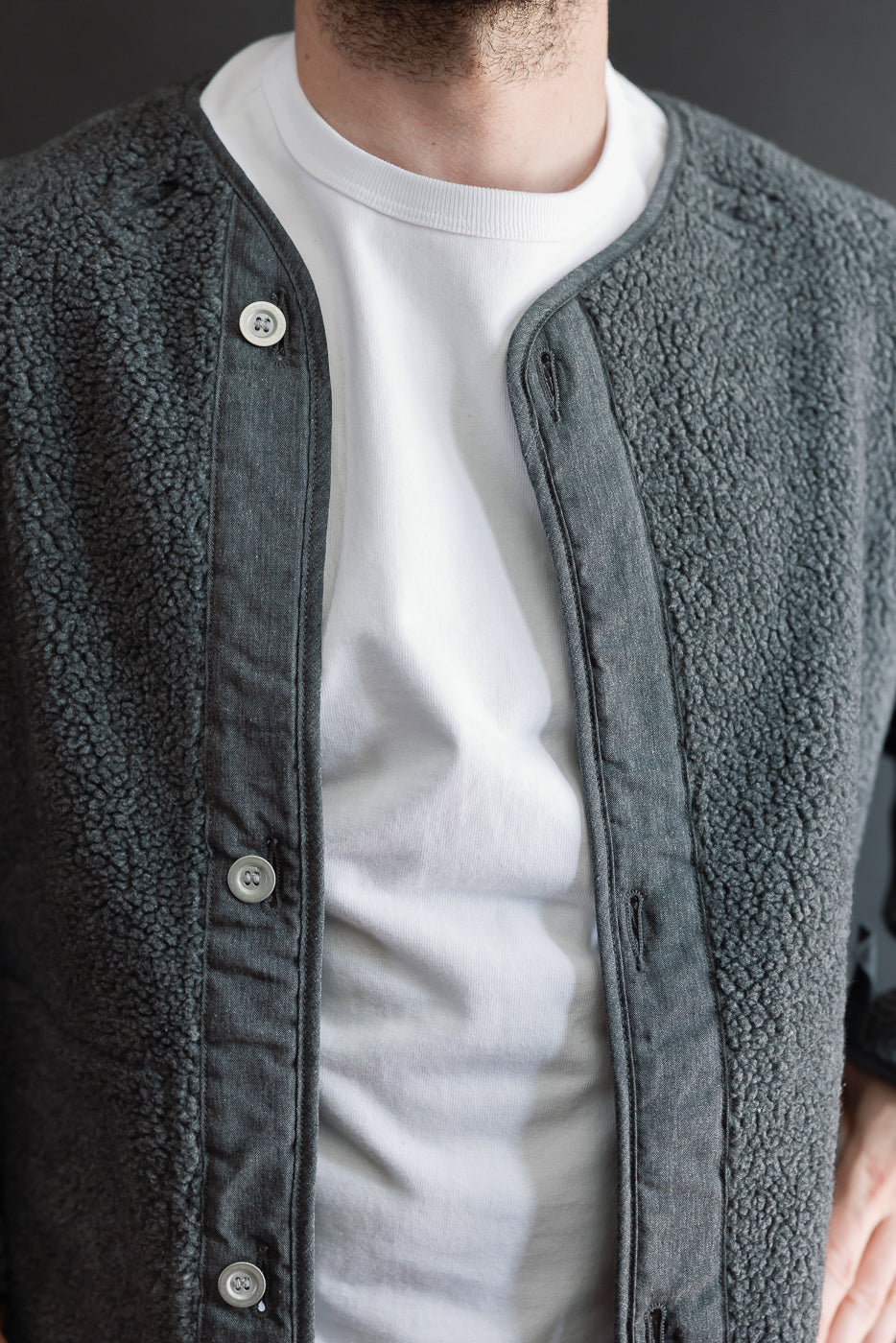 Close-up front view of a charcoal grey sherpa fleece jacket over a white t-shirt on a male model.