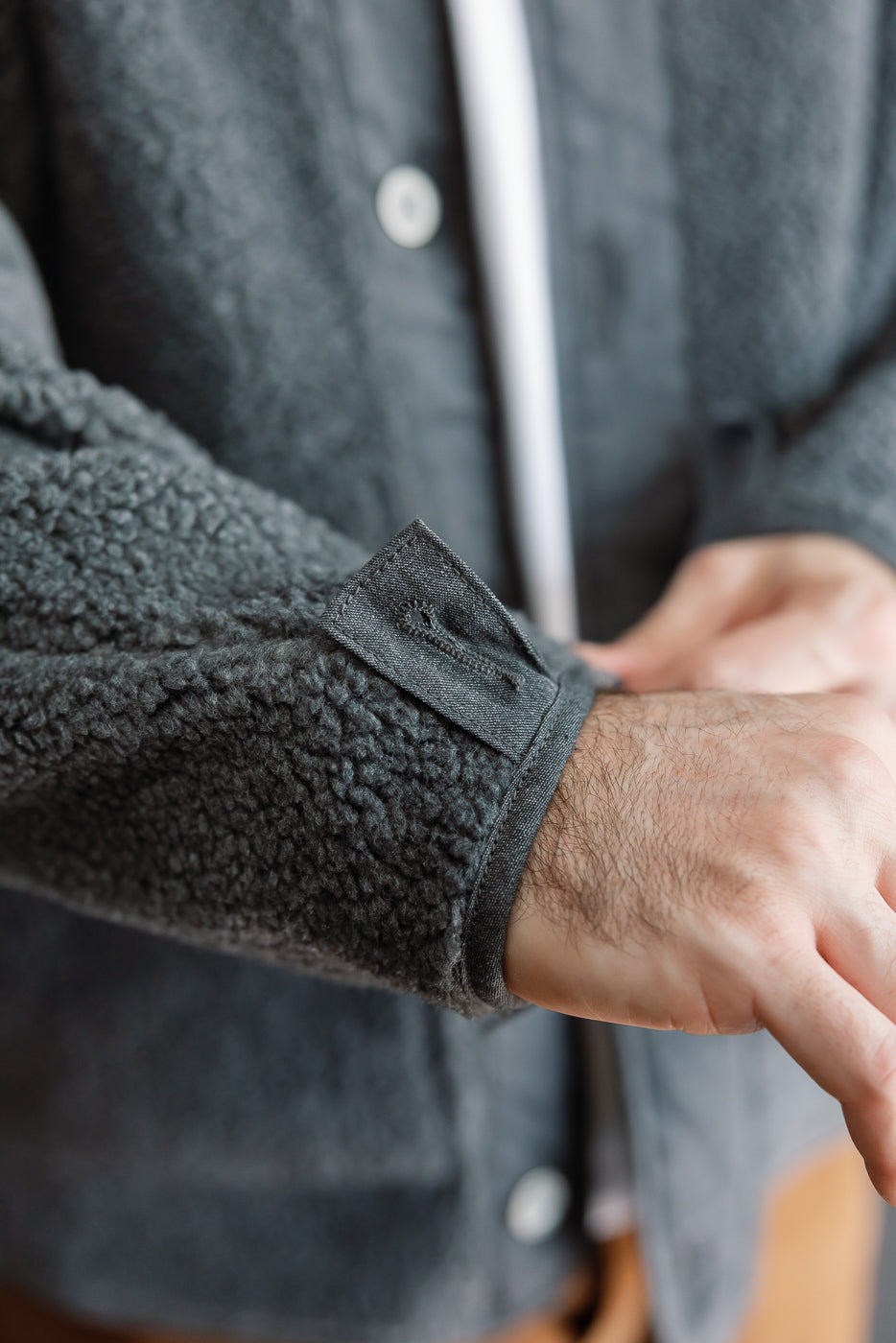 Close-up of the left sleeve cuff and velcro strap on a grey textured fleece jacket.
