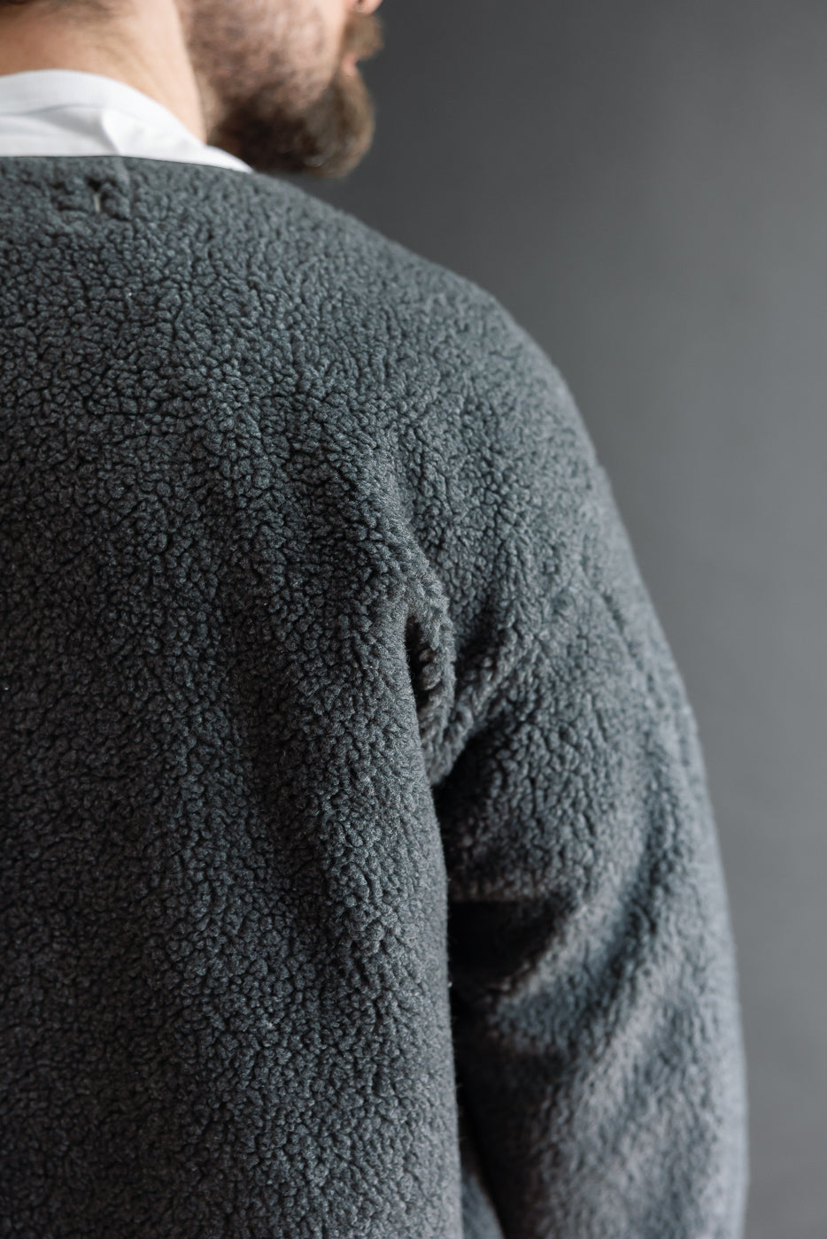 Close-up back view of a male model wearing a grey sherpa fleece jacket showing the texture.