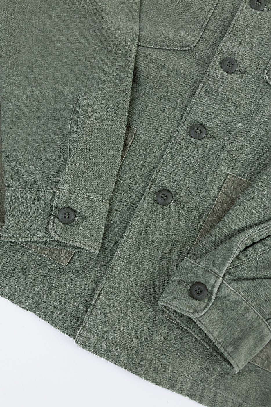 Close-up of orSlow 4-pocket fatigue shirt front in dark olive sateen, button cuffs, fabric texture, lower half detail.