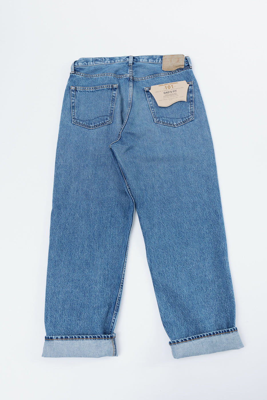 Back view flat lay of light wash denim Dad's Fit jeans with cuffed hems.