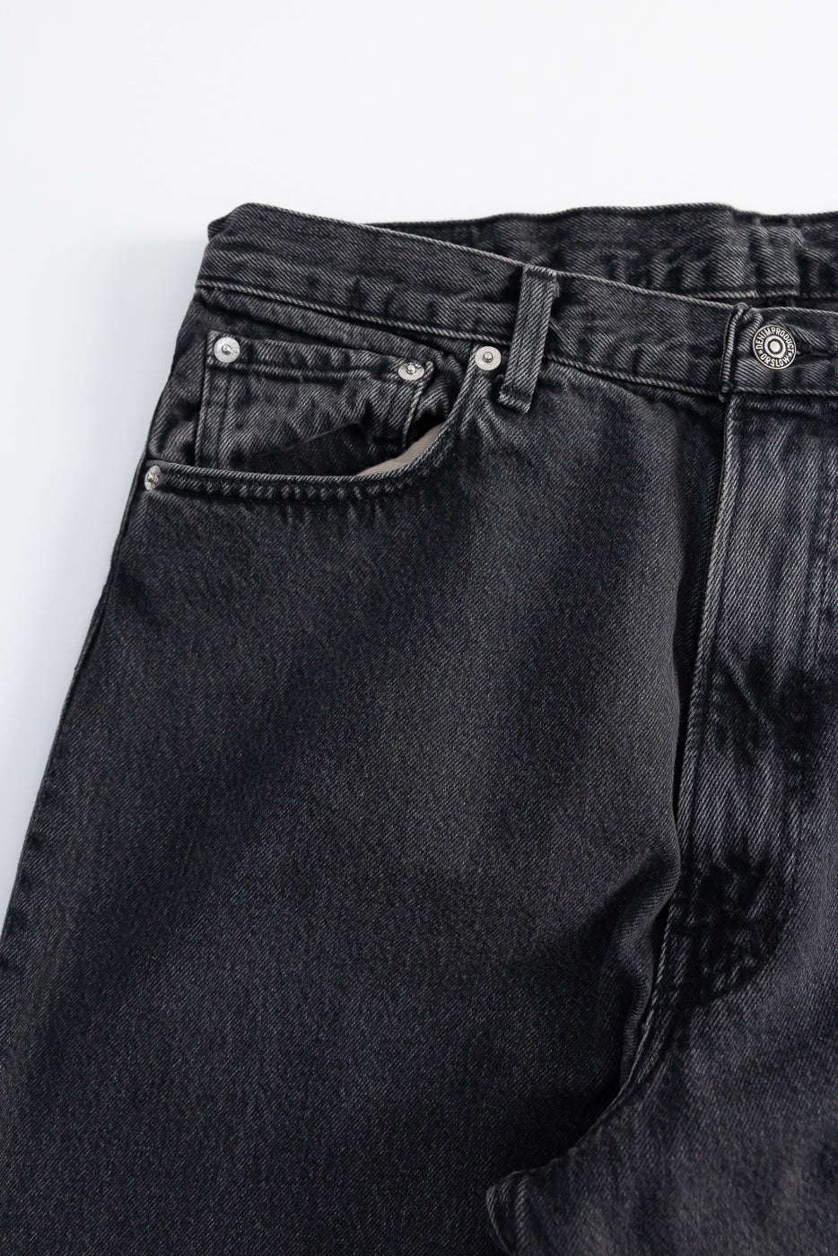 Close-up front view of Orslow black denim jeans, showing pocket, rivets, and button details