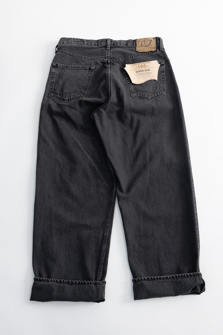 Flat lay of Orslow Super Dad Fit black denim jeans showing back side, rear pockets, tags, and cuffed hems.