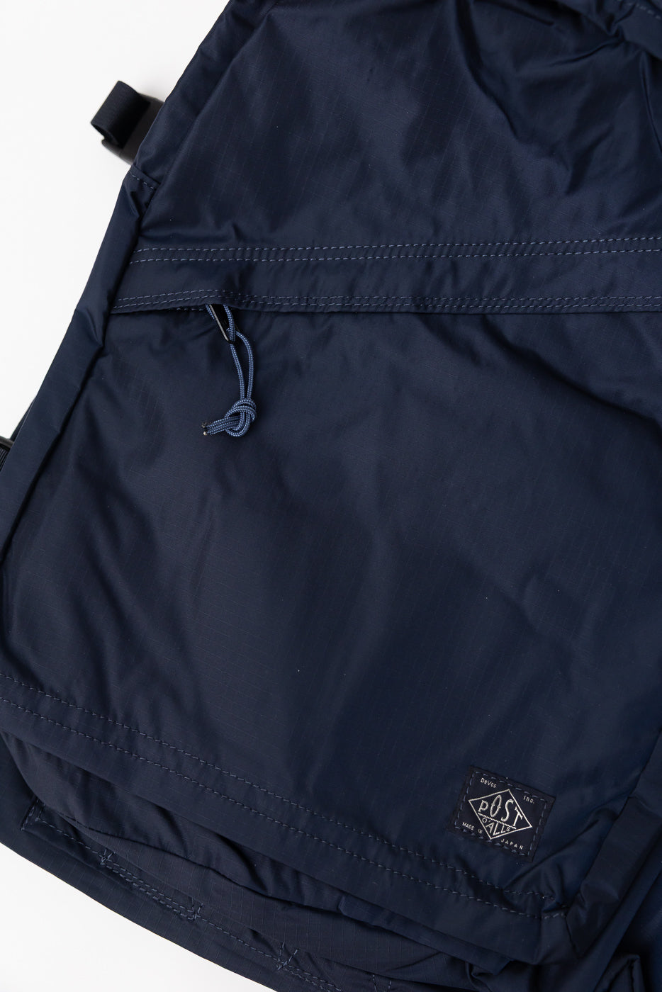 Close-up front of navy Post O'Alls 1931 NRN-A III pack, showing ripstop nylon, drawstring, and logo tag