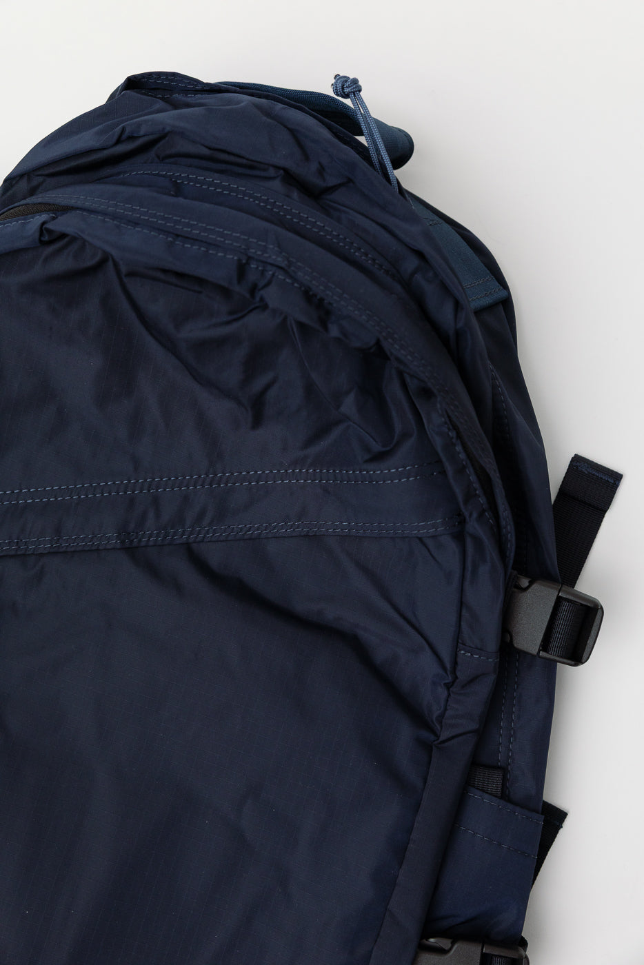 Close-up of navy nylon ripstop backpack front, showing fabric texture and stitching detail