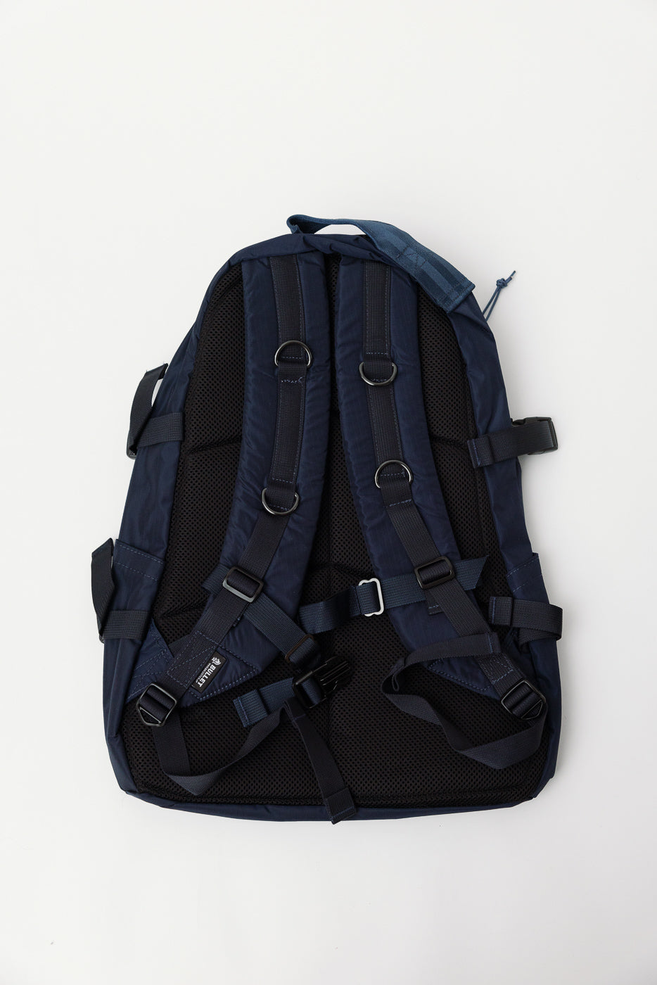 Flat lay of navy nylon ripstop backpack, back view showing padded straps and black mesh panel.