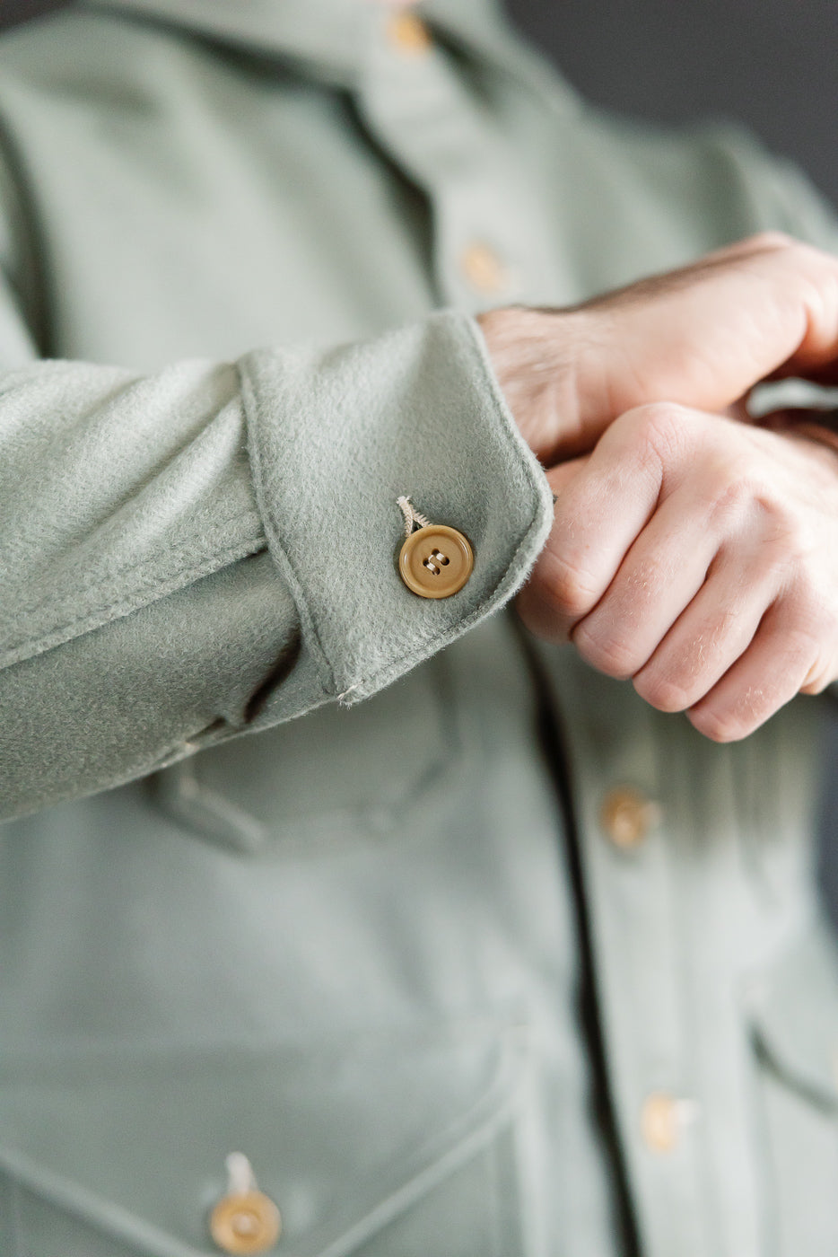 Close-up of cuff and sleeve button detail on pale green Post O’Alls Cruzer 5-R Beaver Melton jacket, shown on male model, highlighting fabric texture and front of garment.