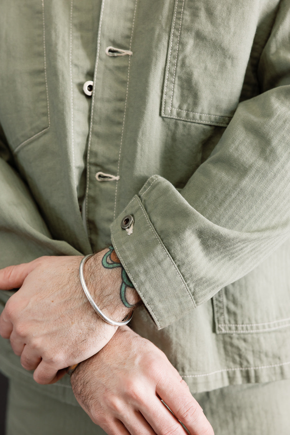 Close-up of sage utility jacket sleeve, front side, on male model 5'9