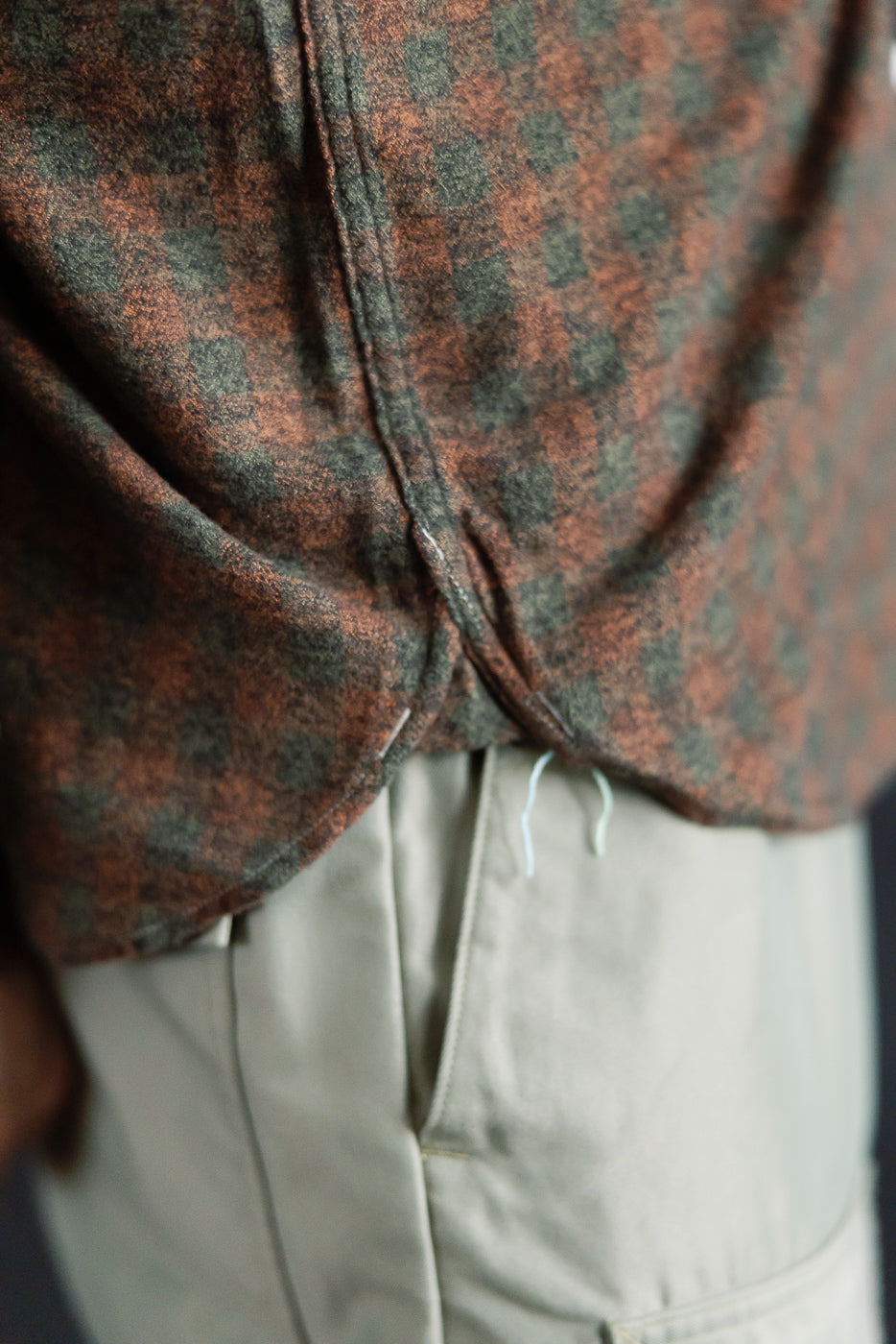 Close-up of Post O'Alls St. Louis plaid flannel shirt hem, side seam, orange and green, worn by male model, Dant contemporary casual apparel