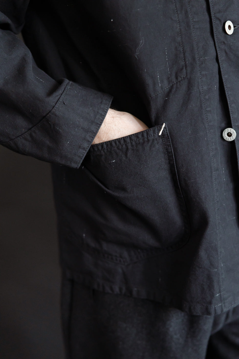 Close-up of male model wearing black Nep Twill coverall, front left pocket and buttons visible