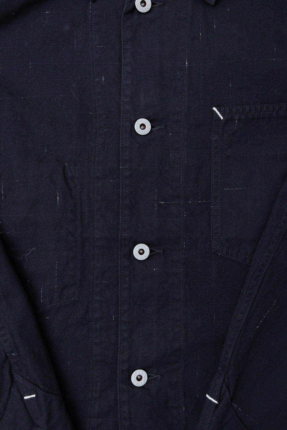 Close-up of front chest and pocket detail on black nep twill coverall, metal buttons visible
