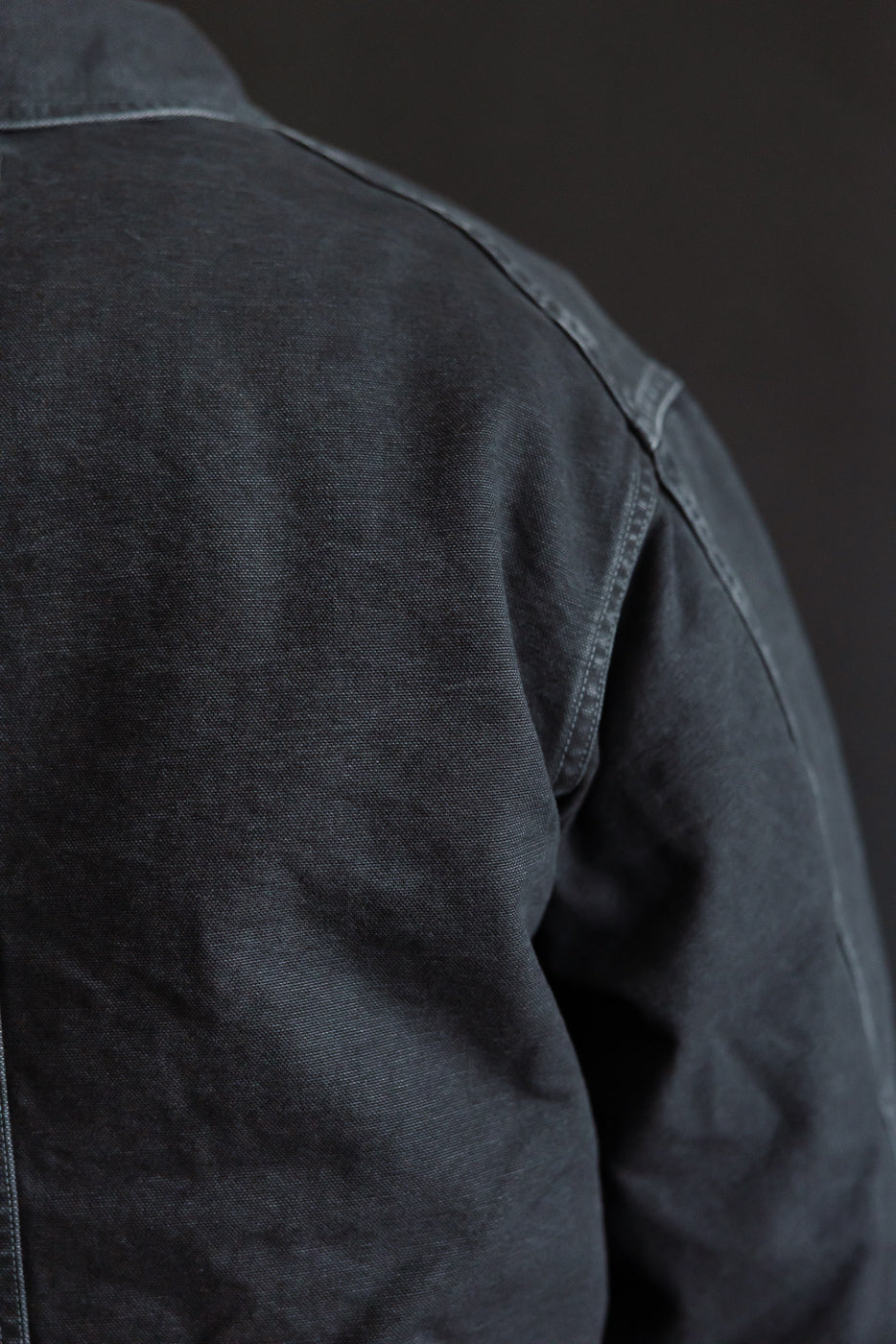 Close-up of back shoulder on Post O’Alls pigment dyed black canvas coverall, showing fabric texture and stitching detail.