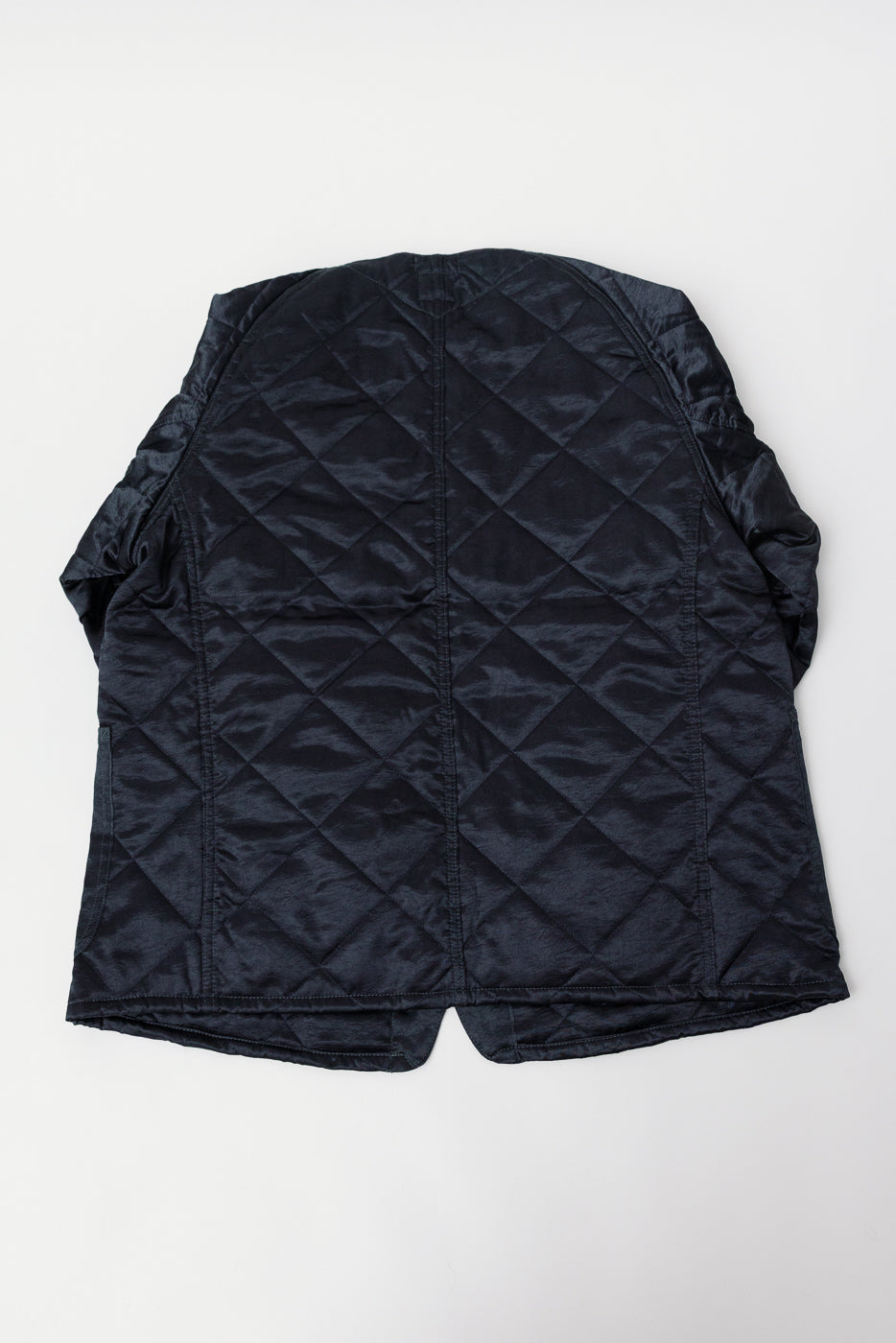 Flat lay of Post 47 quilted acetate sateen coverall in dark grey, back view highlighting diamond stitching texture.