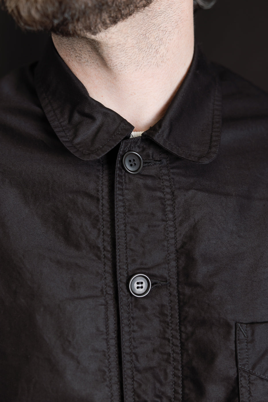 Close-up front view of black moleskin work jacket on male model, 5'9