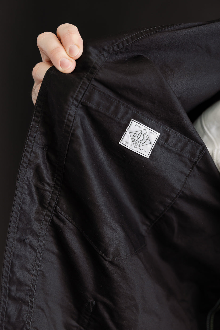Close-up of black moleskin jacket interior, inside front with white woven label detail visible.