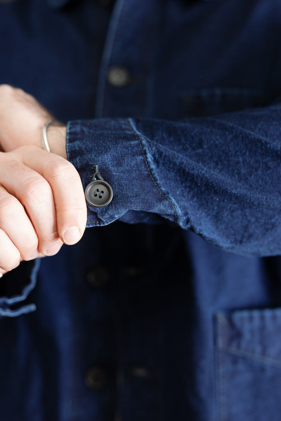 Close-up of male model's sleeve cuff, deep washed indigo canvas, showing button detail, side view, 5'9
