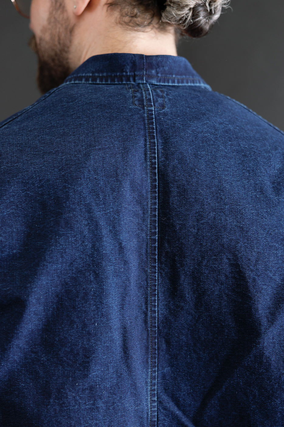 Close-up of back shoulder seam and collar on deep washed indigo canvas shirt, male model.