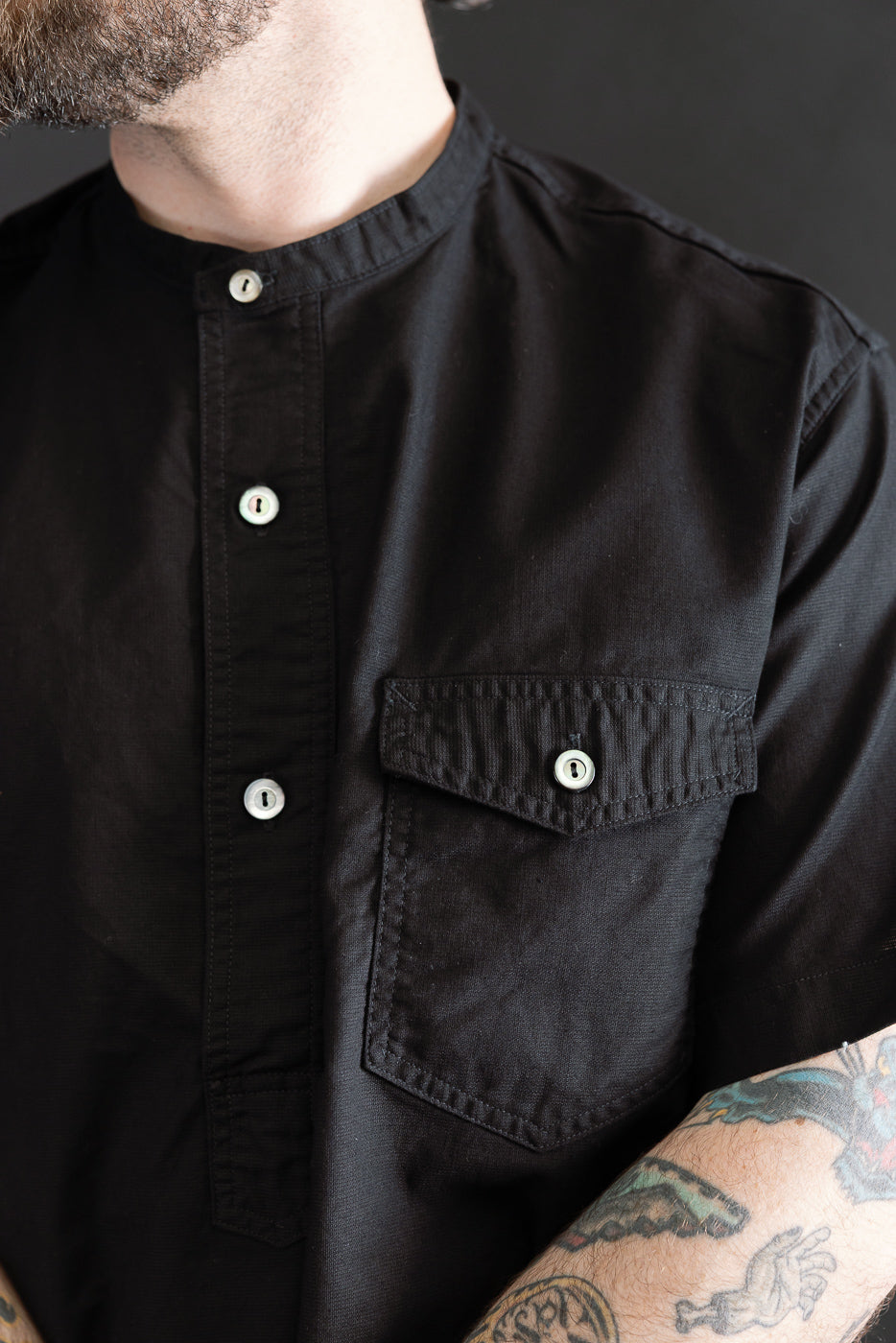 Close-up front of black band collar short sleeve shirt on male model 5'9