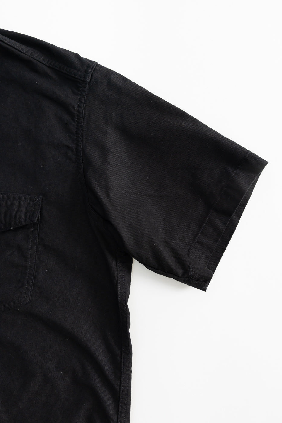 Close-up of short sleeve, front right side of black Panama cloth shirt, showing pocket detail